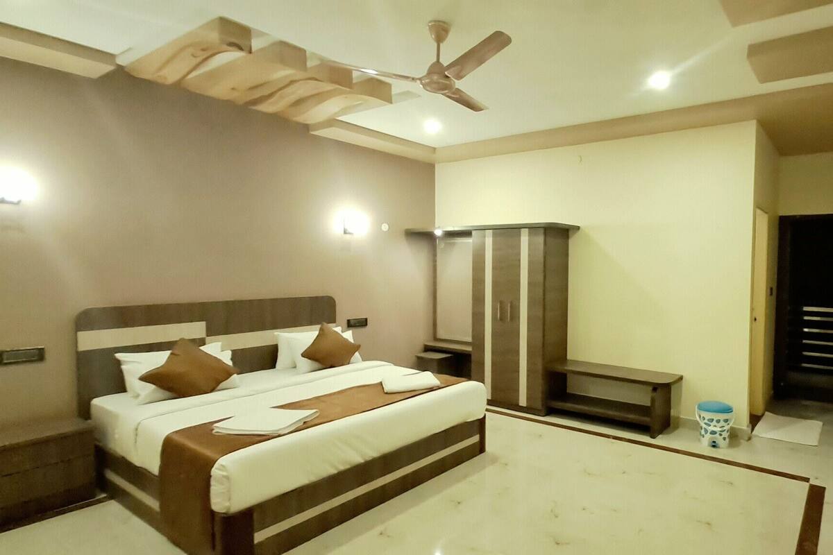 A modern bedroom with a large bed, a wardrobe, a ceiling fan, and a nightstand.