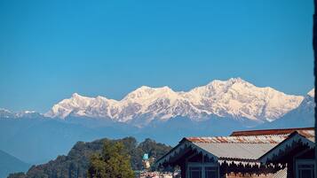 A mountainous landscape with snow-capped peaks and a village with traditional wooden houses.