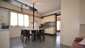 Eine moderne Küche mit Esstisch und Stühlen, einem Fernseher und einer Couch im Wohnbereich.