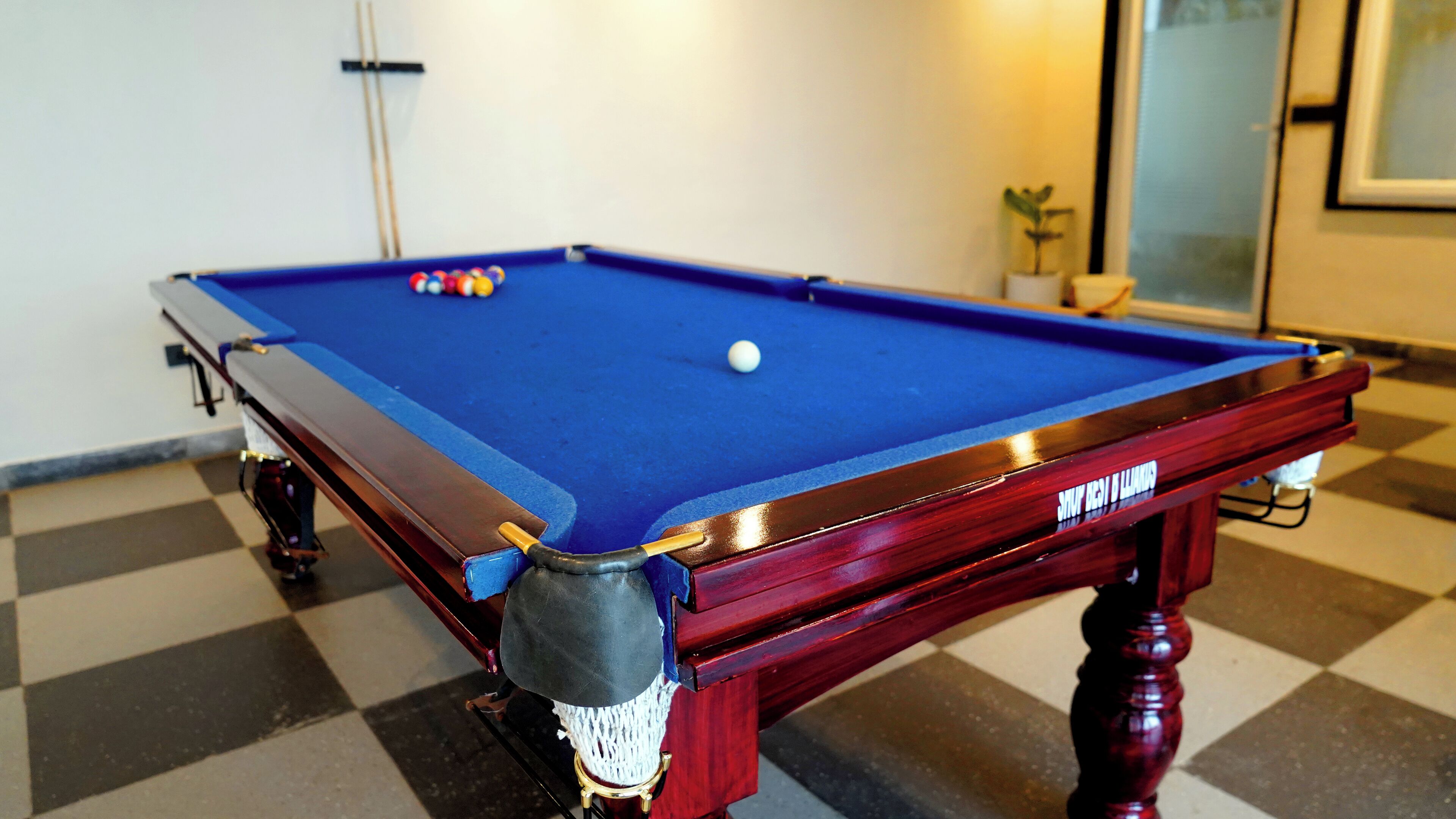 A pool table with balls, a wooden frame, and a checkered floor.