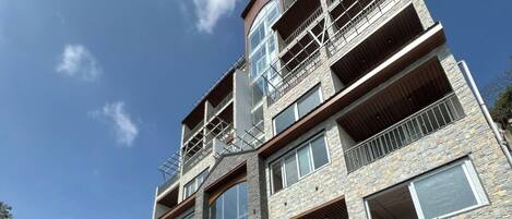 A multi-story building with a stone facade, balconies, and a swimming pool.