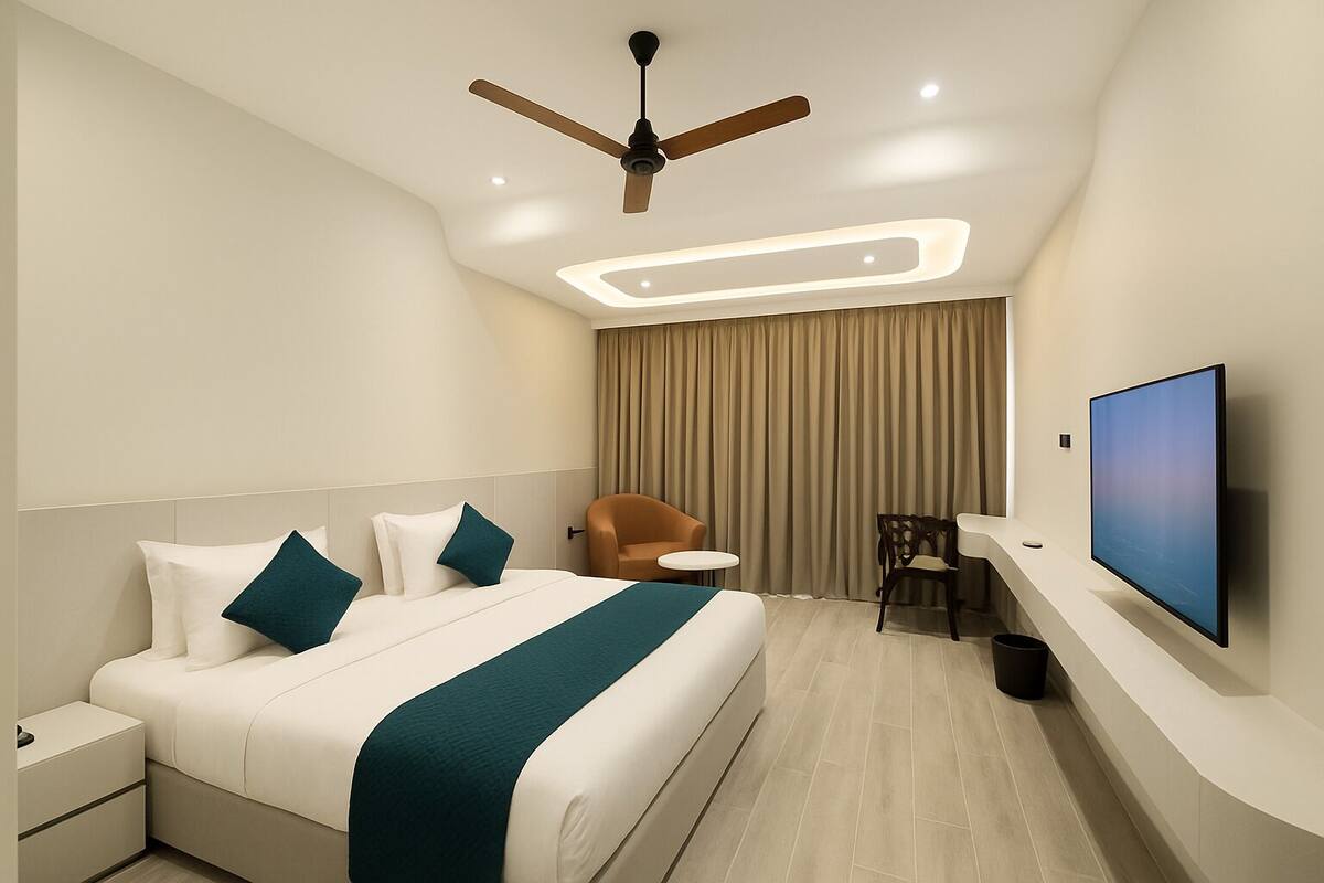 A modern hotel room with a large bed, a ceiling fan, a TV, and a desk area.