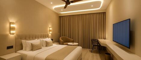 Une chambre d’hôtel moderne équipée d’un grand lit, d’un bureau, d’une chaise, d’un ventilateur de plafond et d’un téléviseur à écran plat.
