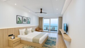 Ein modernes Hotelzimmer mit einem großen Bett, einem Schreibtisch, einem Sessel, einem Fernseher und einem Balkon mit Blick.