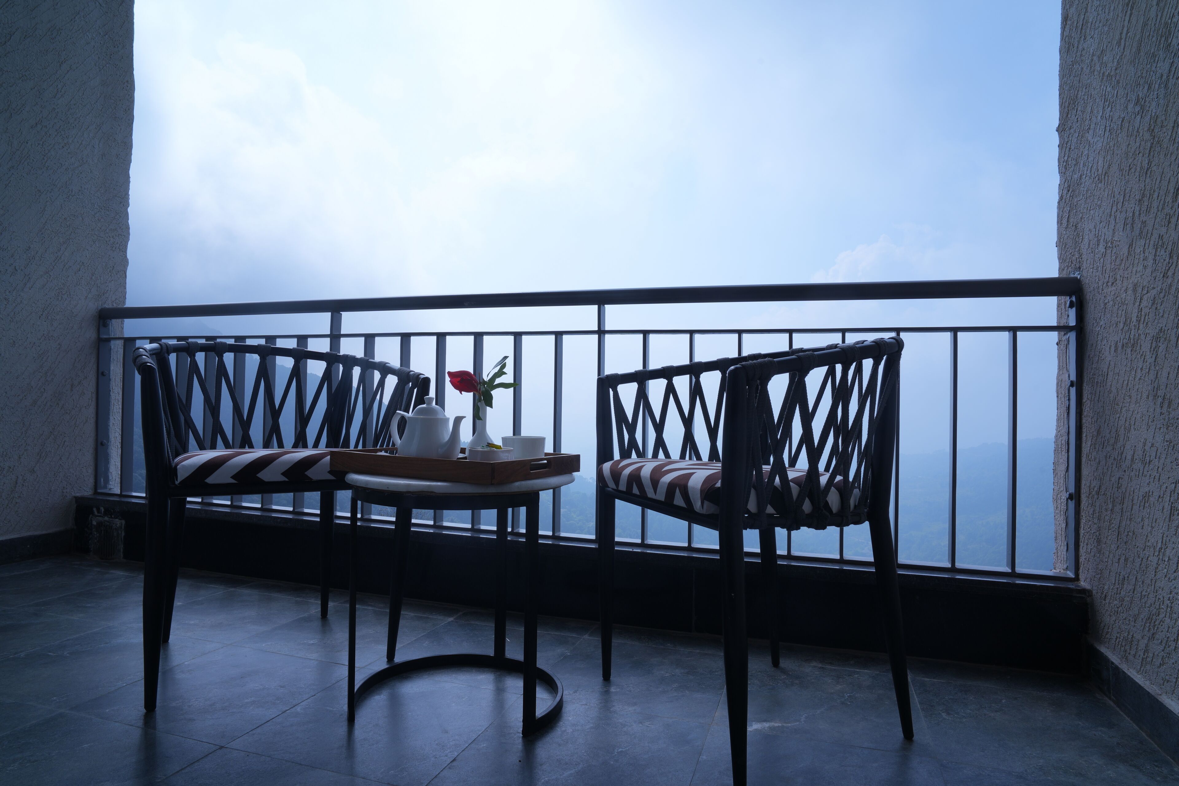 A balcony with two chairs and a table, a view of the sea, and a window with a view of the sea.