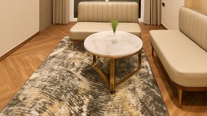 Ein modernes Wohnzimmer mit Deckenventilator, einer Couch, einem runden Couchtisch und Blick ins Freie durch große Fenster.
