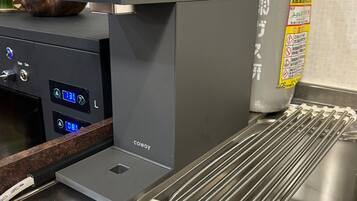 En kaffemaskine med digitalt display, en vanddispenser og en stålvask med et opvaskestativ.
