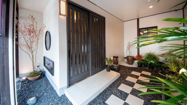 A modern entrance with a checkered floor, a dark wooden door, and potted plants. - Nara-no-ya (Nara)
