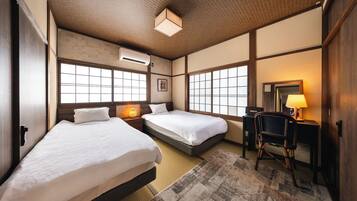 A hotel room with two beds, a desk, a chair, and a large window.