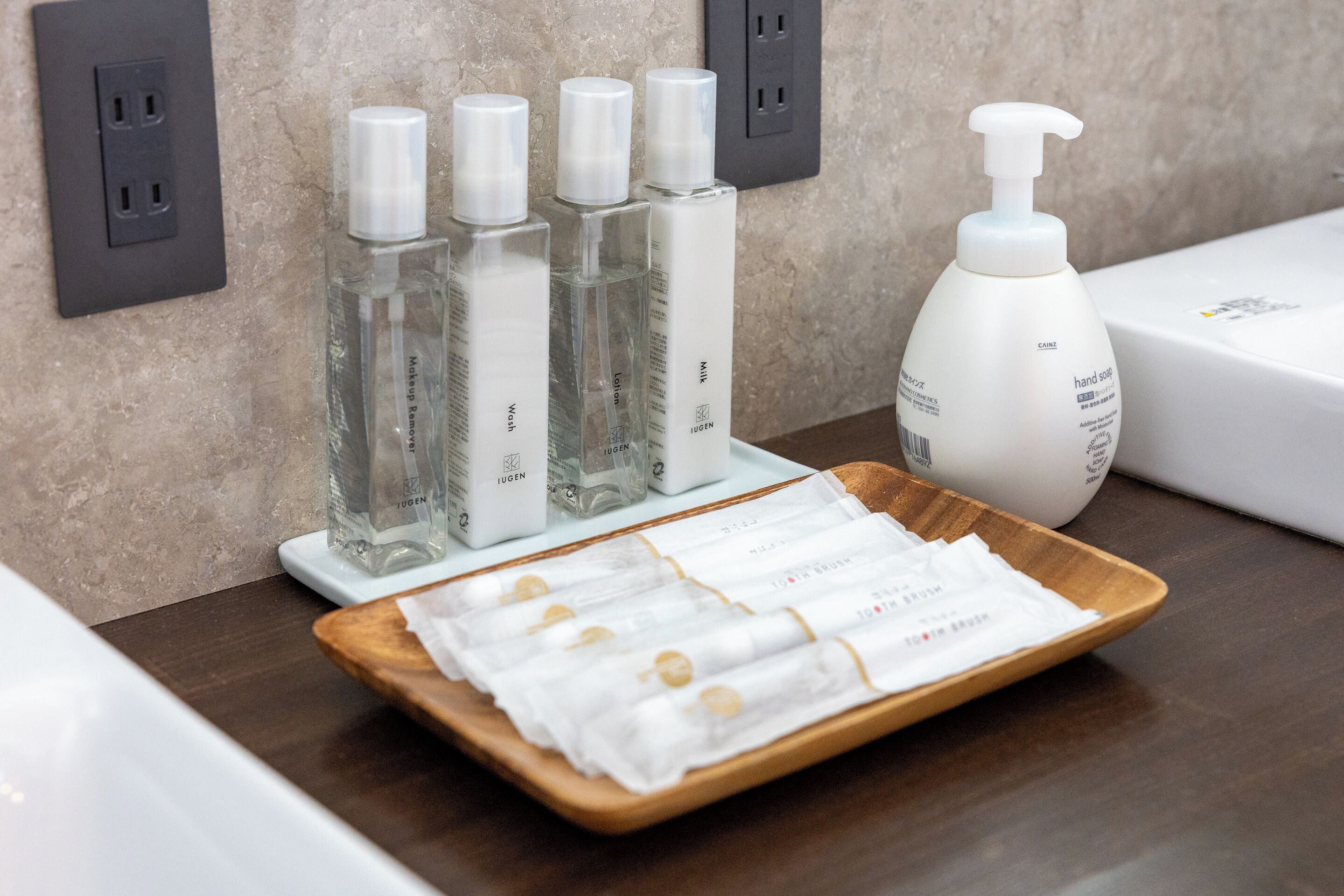 A tray with toiletries including hand soap and lotion bottles, a tissue roll, and a white box, likely for amenities.