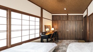 A traditional Japanese-style room with tatami flooring, a desk with a lamp, a wardrobe, and two beds. - Nara-no-ya (Nara)