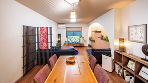 A modern living room with a wooden dining table, black and red patterned partition, and a large window with a view. - Nara-no-ya (Nara)