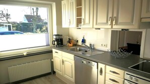 Una cocina moderna con gabinetes blancos, lavavajillas de acero inoxidable y horno empotrado.