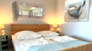 A neatly made bed with white linens, a woven headboard, and two bedside lamps. - Coastal Apartment with Balcony (Fehmarn OT Burgtiefe-Südstrand)