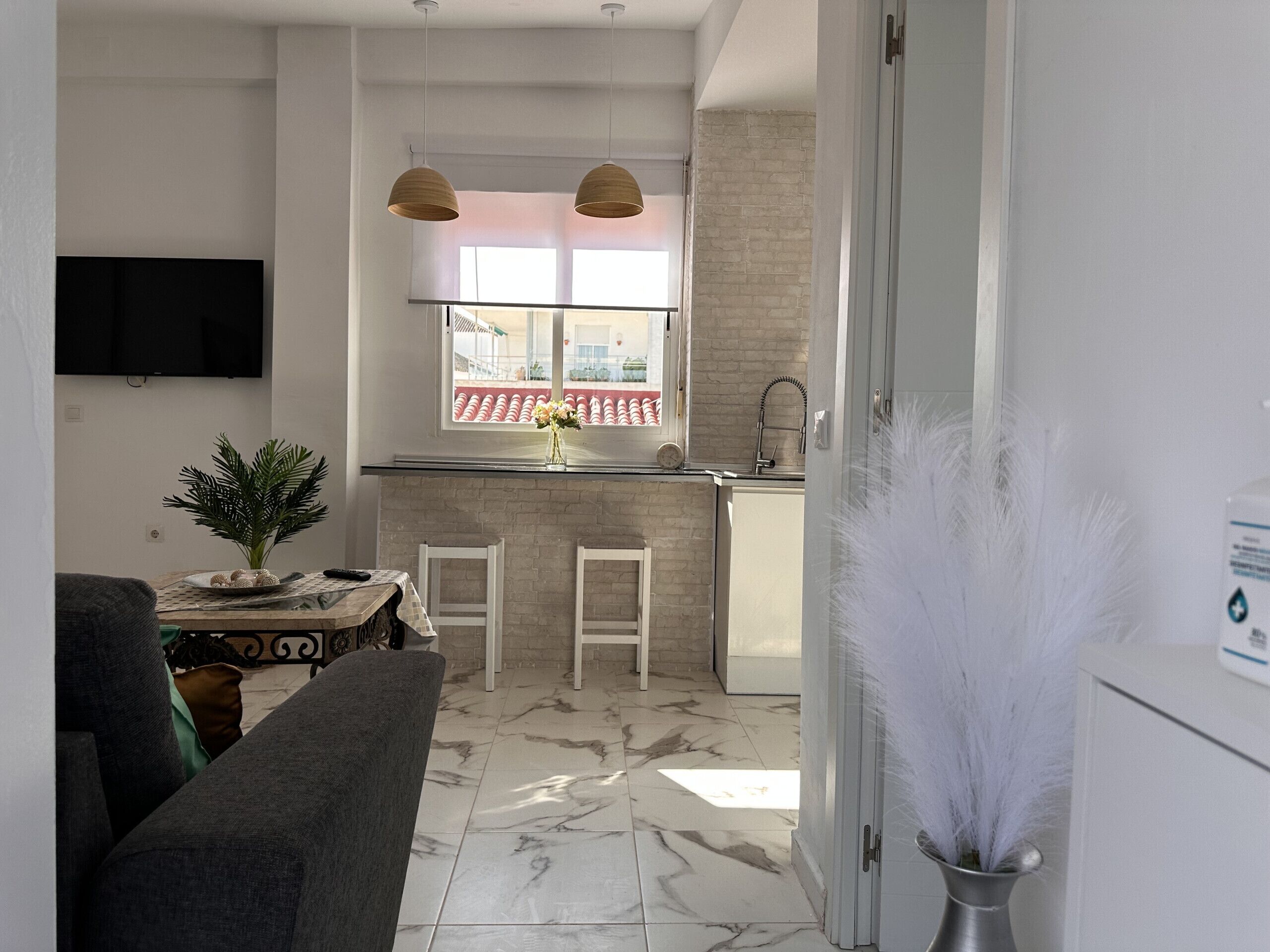 Una cucina moderna con mobili bianchi, una finestra con vista e un'area pranzo con tavolo e sedie.