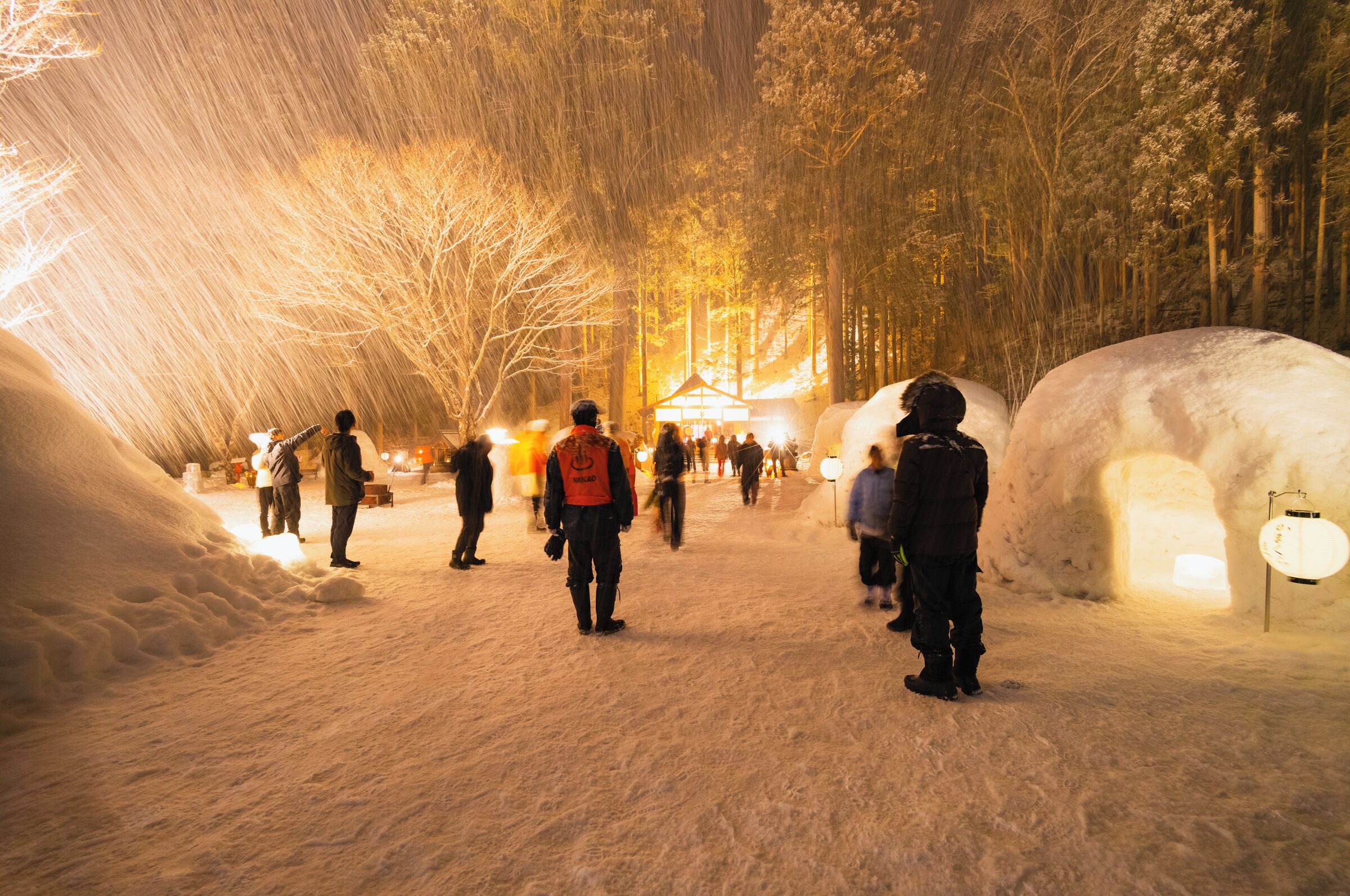 A snow-covered path with igloos and a tented area in the background.