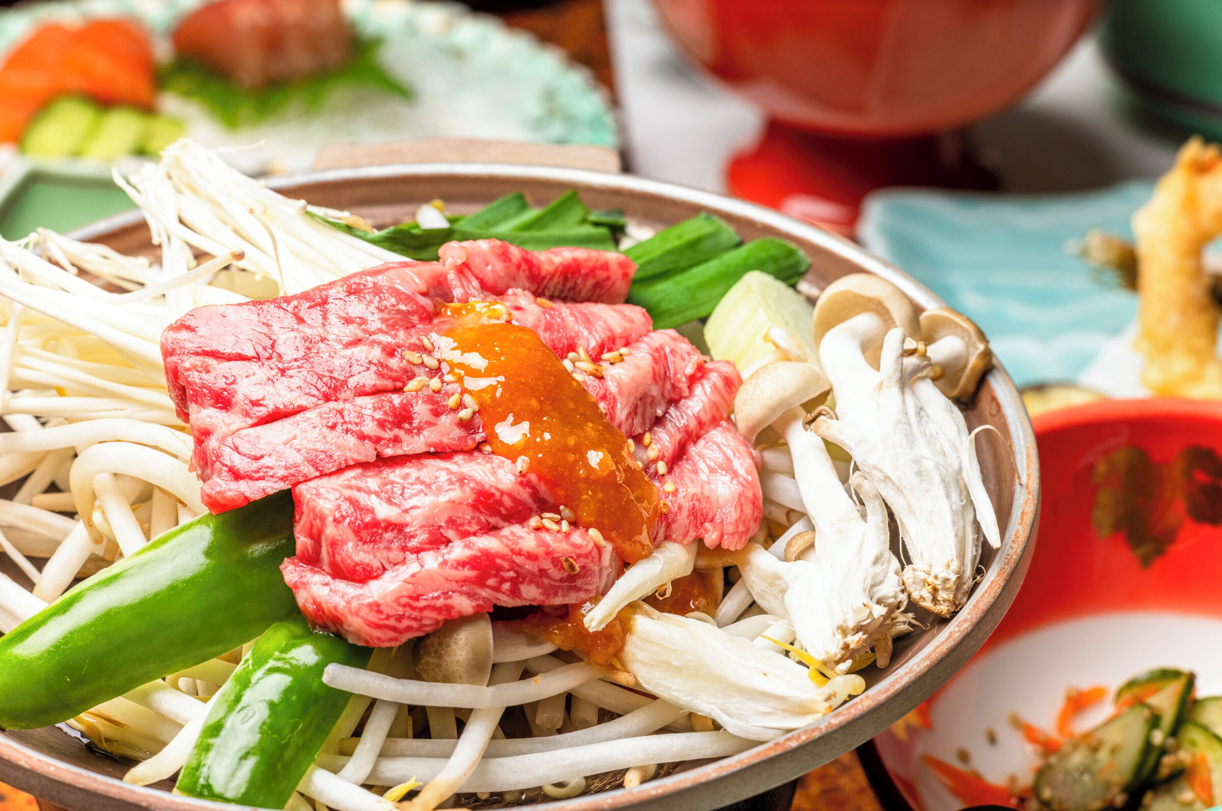Un bol de ramen garni de divers ingrédients, notamment de la viande, des légumes et une sauce.