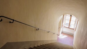 A staircase with a metal handrail leading to a bright, sunlit room with a tiled floor. - Sanniccolo'20 - Historic Residence (Arezzo)