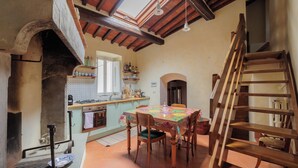A rustic kitchen with a wooden table, chairs, and a wooden staircase. - Sanniccolo'20 - Historic Residence (Arezzo)