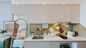 A modern kitchen with a built-in sink, white cabinets, and a mirror. - Vinhomes Ocean Park Apartment FL09 (Hanoi)