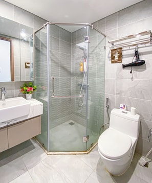 Un baño moderno con ducha envuelta en vidrio, inodoro blanco y lavamanos con encimera de mármol.