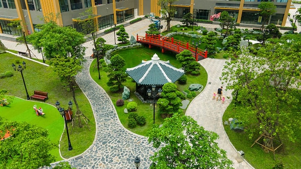 A courtyard with a traditional pavilion, a red bridge, and a stone pathway. - Vinhomes Ocean Park Apartment FL09 (Hanoi)