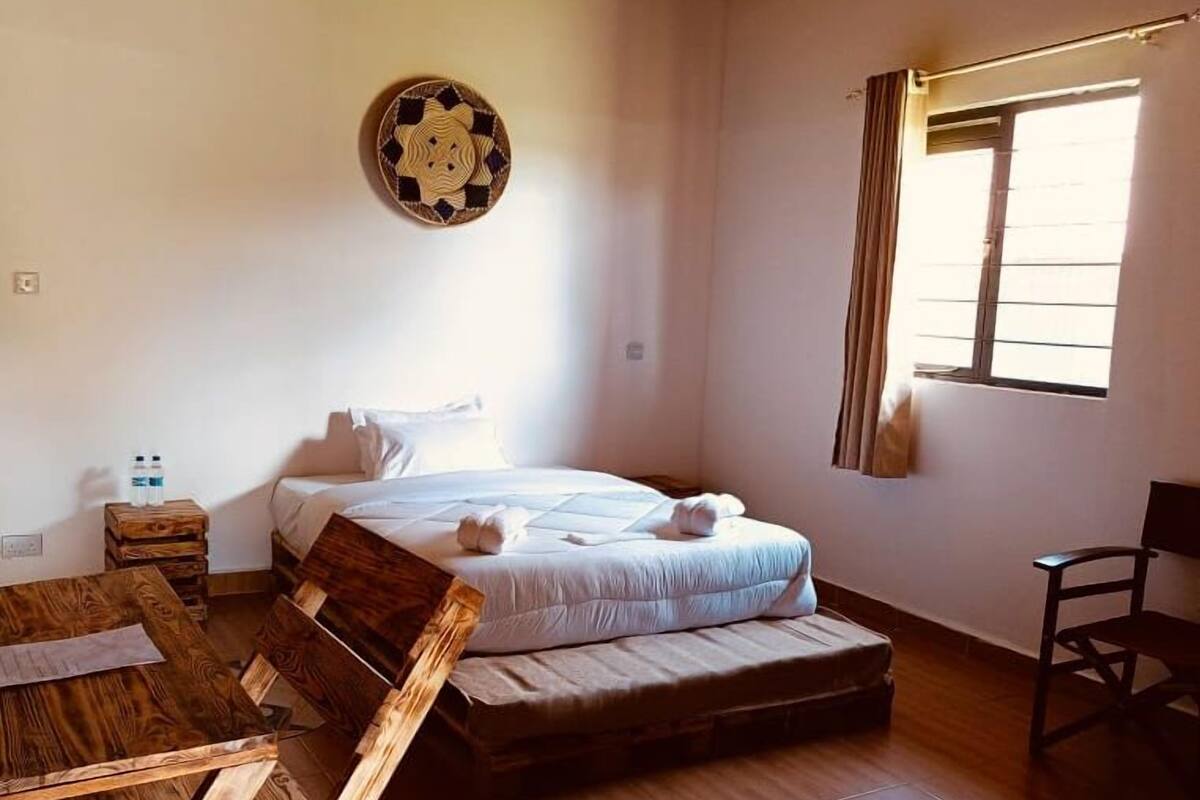 Un dormitorio con una cama, una mesa de madera, una silla, una ventana y una decoración en la pared.