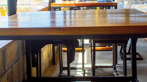 An indoor dining area with tables and chairs, a large tree, and a view of the outside through large windows. - Captain James Camp (Naivasha)