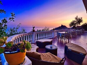 A terrace with outdoor seating, a view of the sea, and a sunset. - LA COLLINA SUL MARE (Palma di Montechiaro)