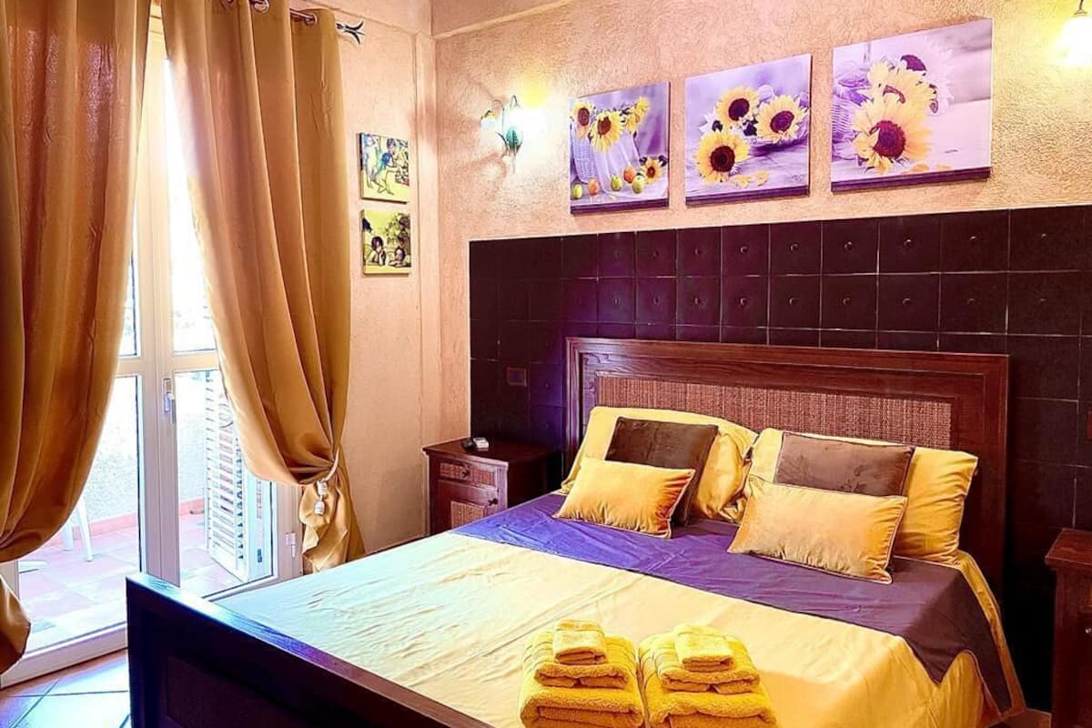 A hotel room with a large bed, a headboard, and artwork on the wall.
