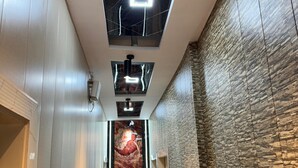 Un corridoio moderno con pavimento in marmo, parete a motivi bianchi e neri e soffitto con illuminazione a incasso.