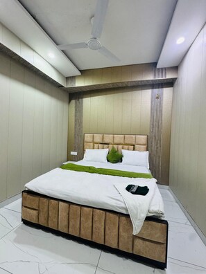 A modern bedroom with a large bed, a ceiling fan, and a nightstand.
