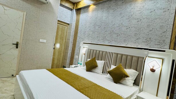 Una camera d'albergo moderna con un letto grande, un comodino, un ventilatore a soffitto e un condizionatore.