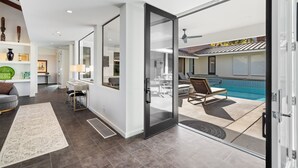 A modern living room with a glass door leading to a pool area. - Ozone Pool, Spa and Built-In Bar (Palm Springs)