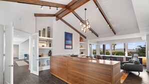 A modern kitchen with a wooden island, open shelving, and a view of the outdoors. - Ozone Pool, Spa and Built-In Bar (Palm Springs)