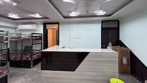 A hotel room with bunk beds, a central island, a ceiling with recessed lighting, an air conditioning unit, and a water dispenser. - Aarav Dormitory (Itarsi)