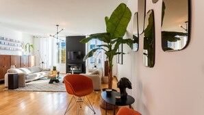 A modern living room with a sofa, a coffee table, and a large plant. - PORT LYMPIA AP4429 By Riviera Holiday Homes (Niza)