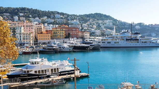A marina with various boats docked, a large yacht, and colorful buildings in the background. - PORT LYMPIA AP4429 By Riviera Holiday Homes (Niza)