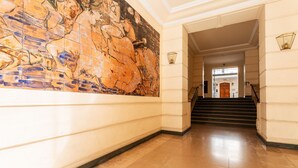 A hallway with a large mural, a staircase, and a door at the end. - LE LAFAYETTE AP4410 By Riviera Holiday Homes (Niza)