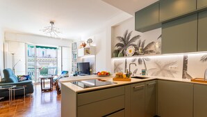 A modern kitchen with a built-in island, a dining area with a sofa and table, and a living room with a sofa and a TV. - LE LAFAYETTE AP4410 By Riviera Holiday Homes (Niza)