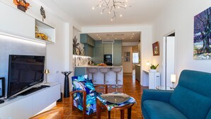 A modern living room with a TV, sofa, and a dining area with bar stools. - LE LAFAYETTE AP4410 By Riviera Holiday Homes (Niza)