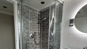 A modern bathroom with a glass-enclosed shower, a white sink, and a mirror.