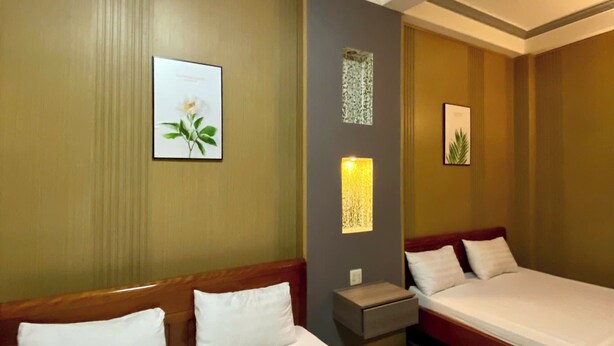 Une chambre d’hôtel avec deux lits, une table de chevet et des lampes fixées au mur.