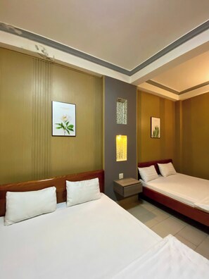 A hotel room with two beds, a nightstand, and wall-mounted lamps.