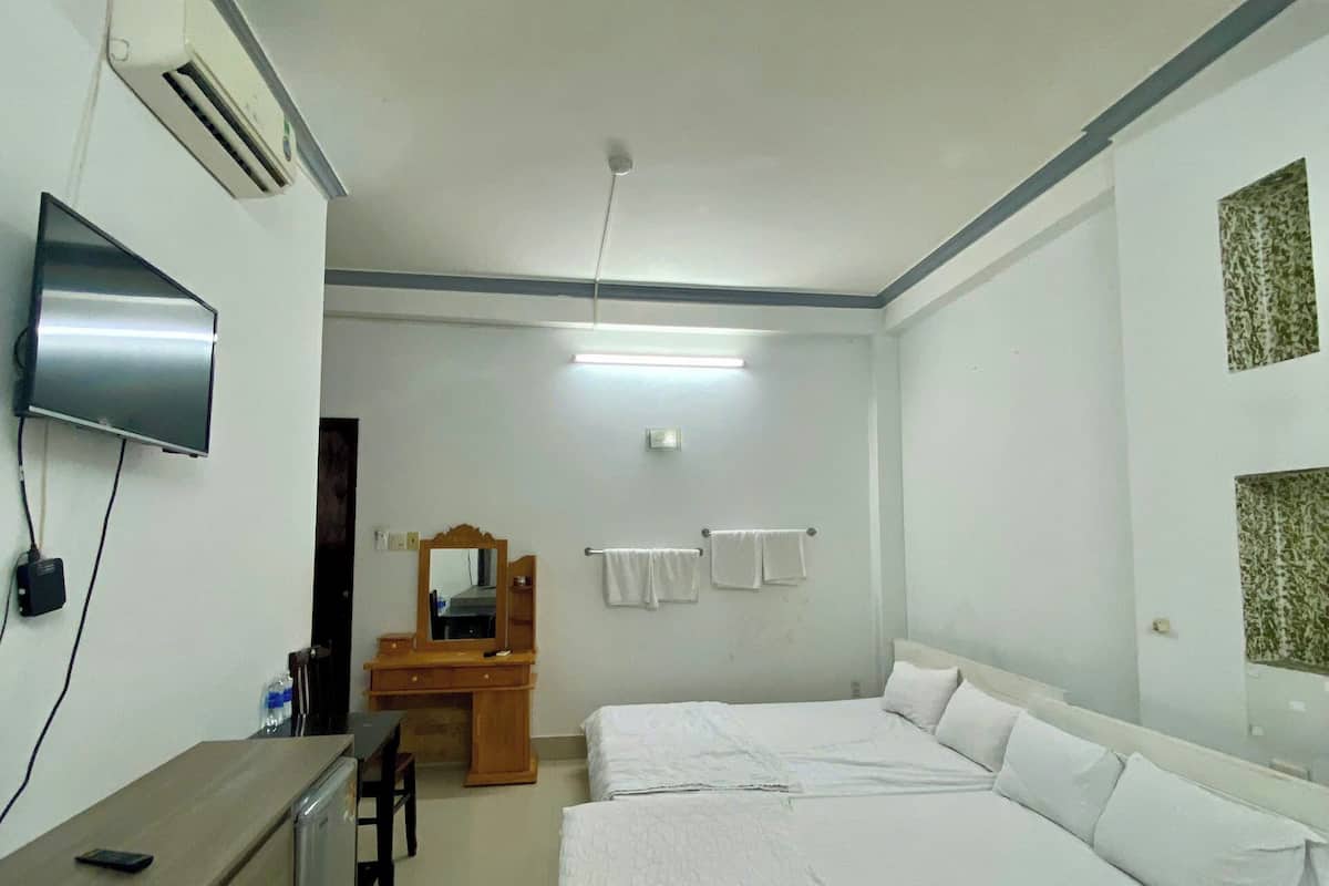 Una habitación de hotel con cama, escritorio, televisor y espejo.
