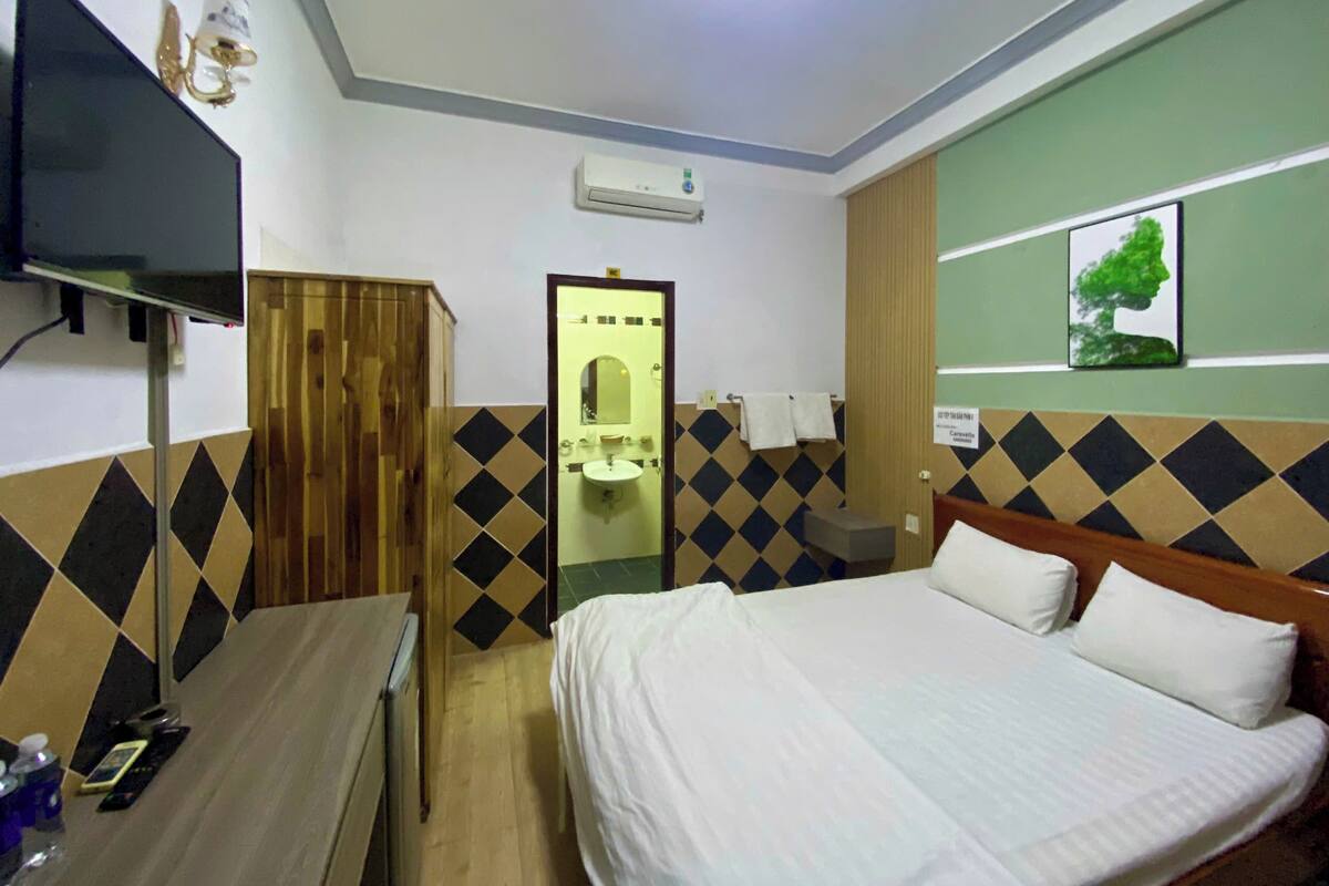 Una habitación de hotel con una cama, un escritorio, un espejo y un televisor.