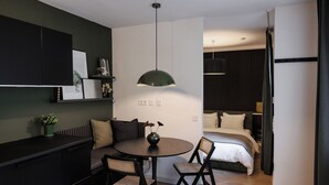 Un espacio habitable moderno y funcional con comedor, cama y kitchenette.