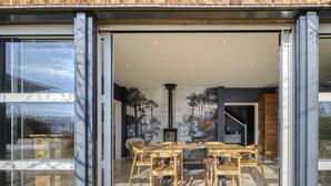 Una casa moderna abierta con comedor amueblado en madera y chimenea.