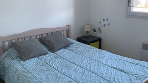 Un lit simple avec une couvre-lit à motifs, une table de chevet avec une lampe et des décorations murales.