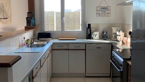 Une cuisine moderne équipée d’un lave-vaisselle, d’une cuisinière et d’une fenêtre donnant sur l’extérieur.